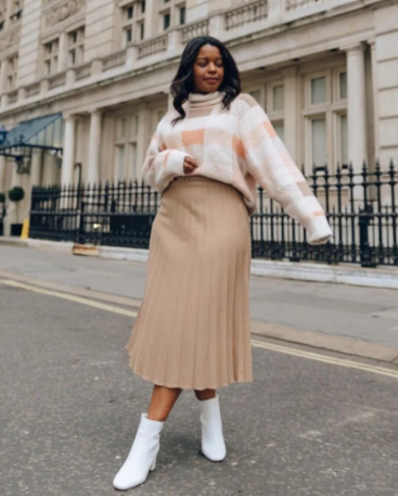 Mulher usando bota, saia midi e tricô em um look de inverno feminino elegante e confortável.